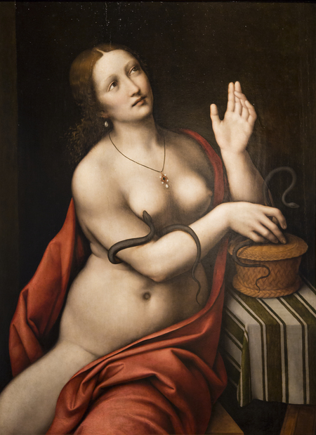Cleopatra seated beside a table, wearing a red mantle and necklace. Her right hand is placed at the top of a basket on the table and her left hand is raised. She looks up left, away from the viewer. Two asps appear, one wrapped around her right arm and the other by her hand and the basket's lid.